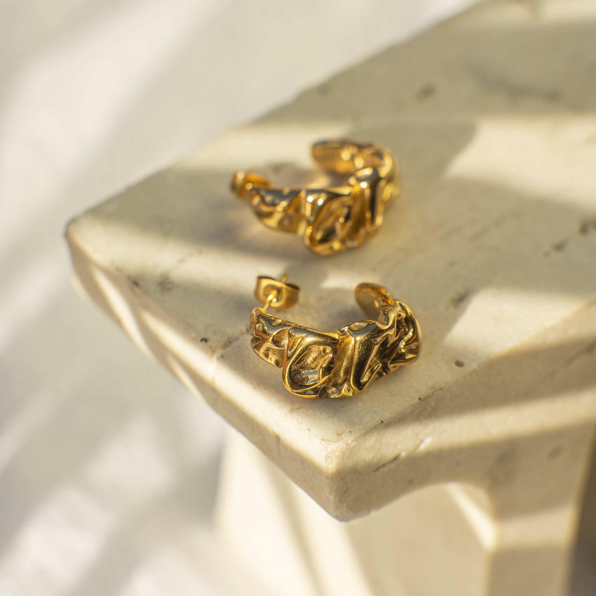 Gold hoop earrings on a marble surface