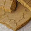 Gold necklace with diamond-shaped pendants on a stone surface