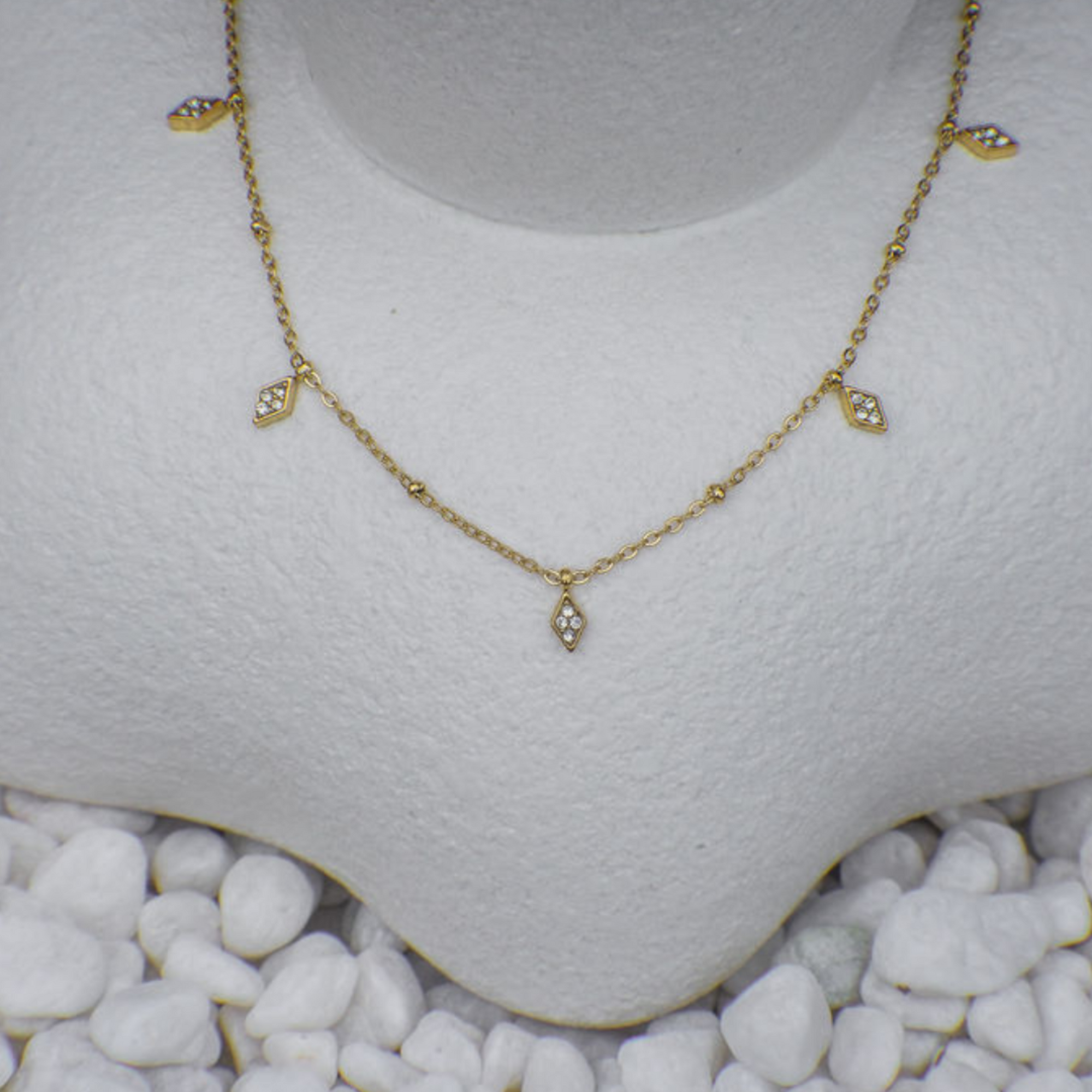Gold necklace on a mannequin bust with a white background