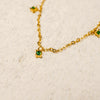 Gold necklace with green gemstones on a beige background