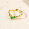 Gold ring with green gemstones on a beige background