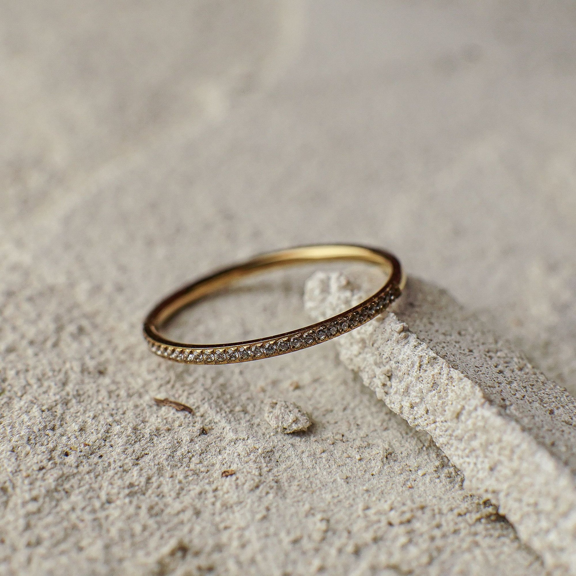 Gold ring with small diamonds on a sandy surface