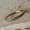 Gold bracelet with embedded stones on a textured surface