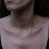 A model wearing a gold necklace with circular pendant and zirconia