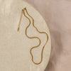 A gold-colored herringbone necklace laid out on a beige surface.