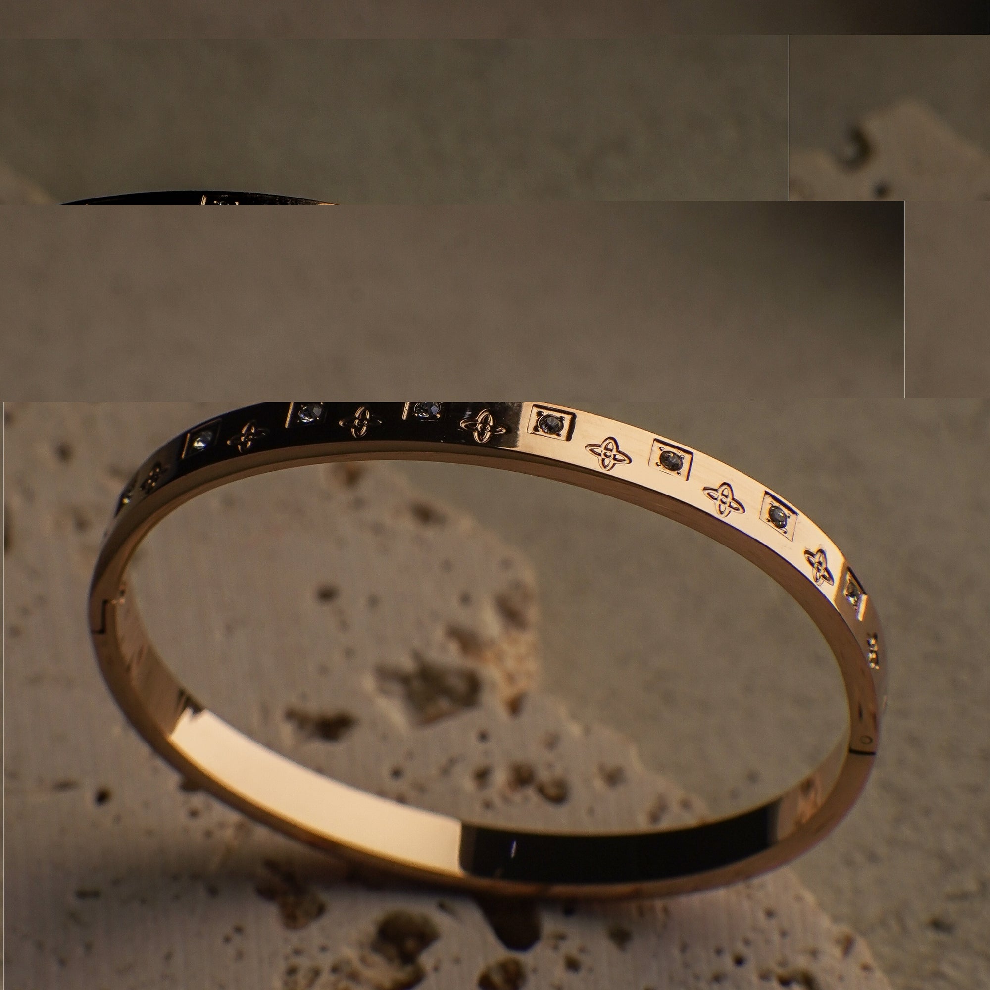 Gold bracelet with engraved designs on a textured surface