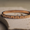 Gold bracelet with engraved patterns on a textured surface