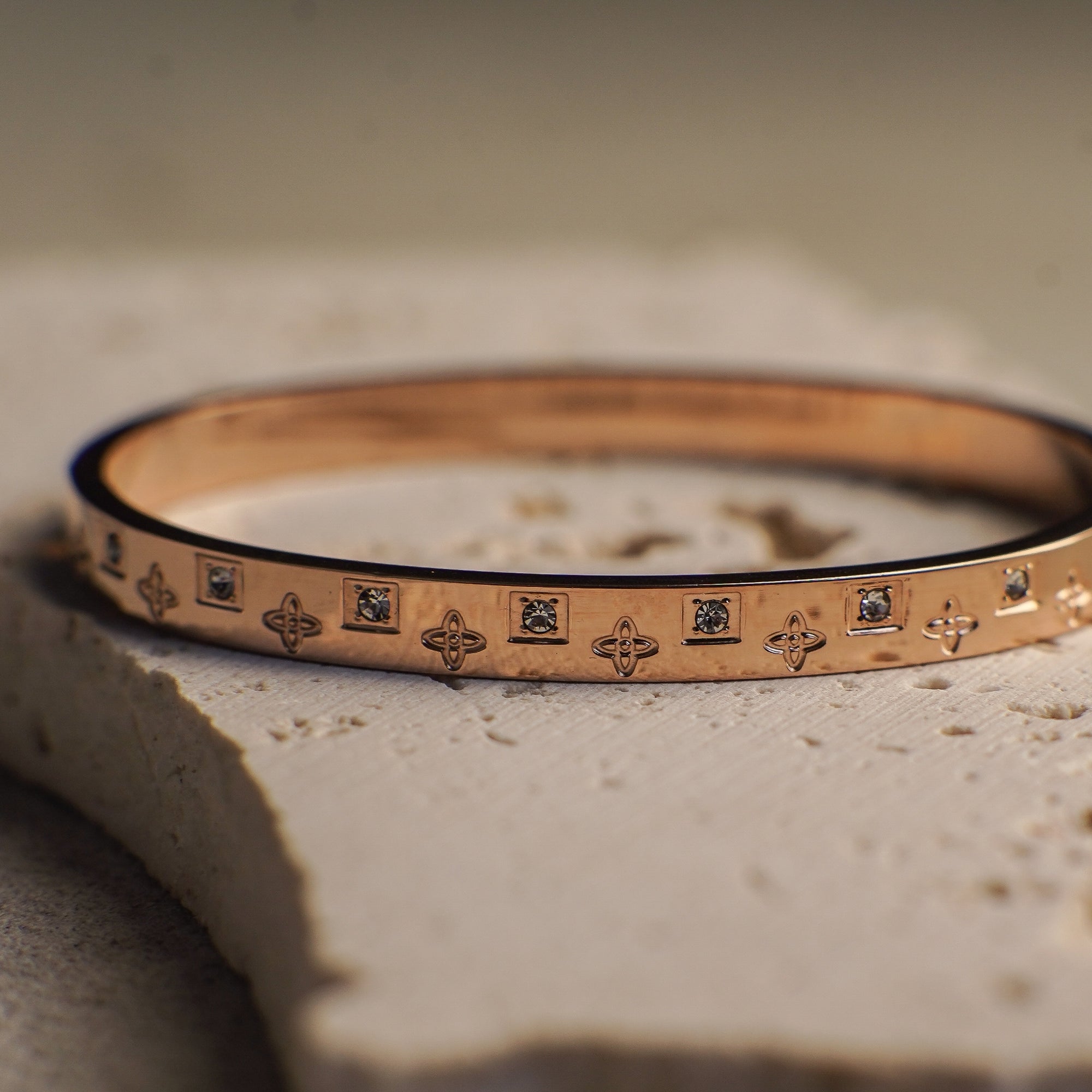 Gold bracelet with engraved patterns on a textured surface