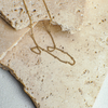 Gold necklace on a textured beige stone surface