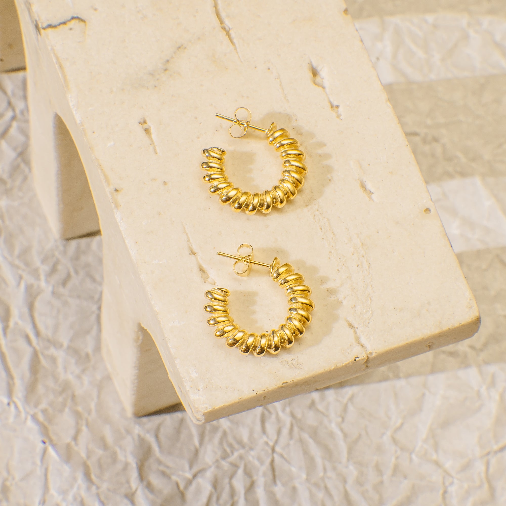 Gold hoop earrings on a marble surface