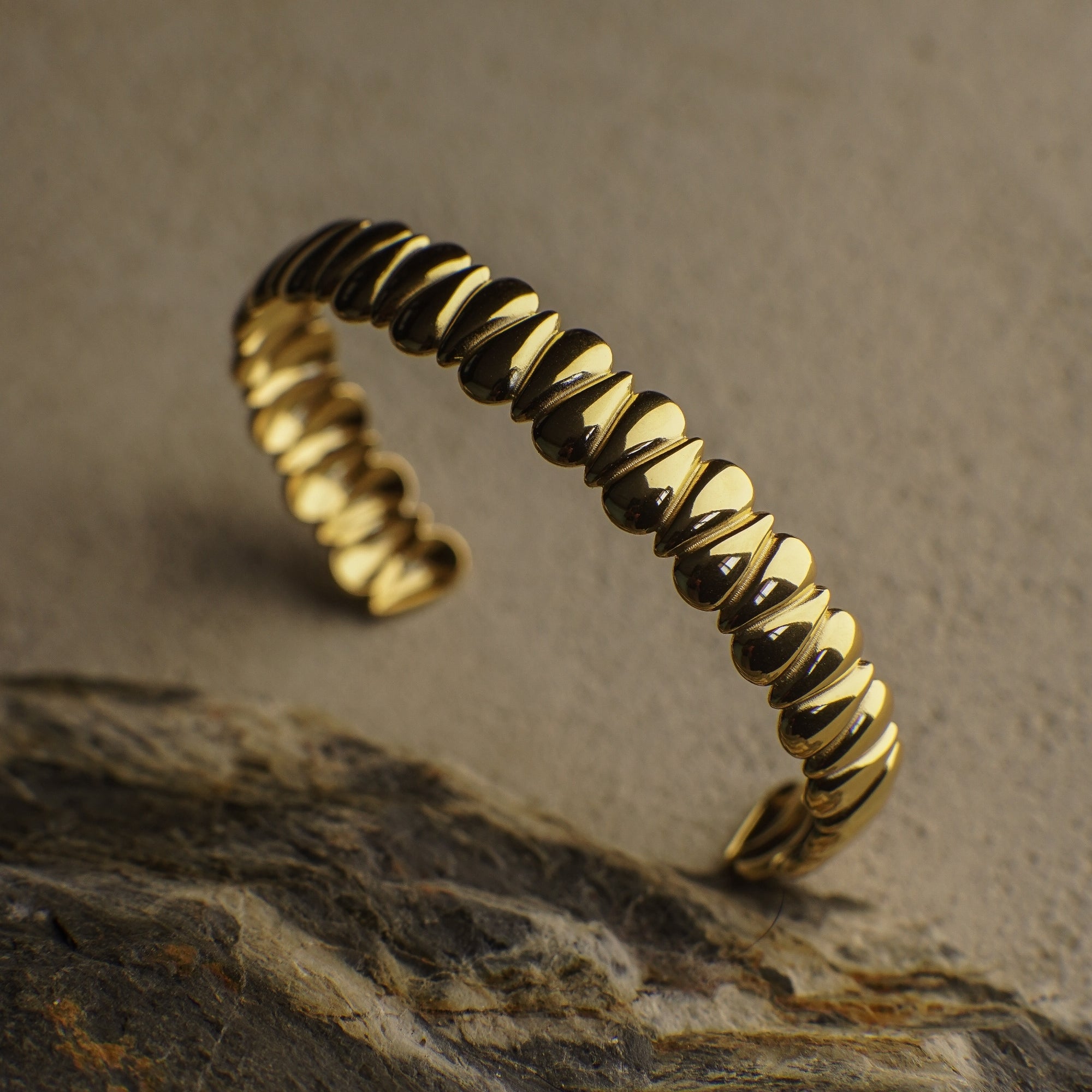 Gold ring with textured design on a stone surface