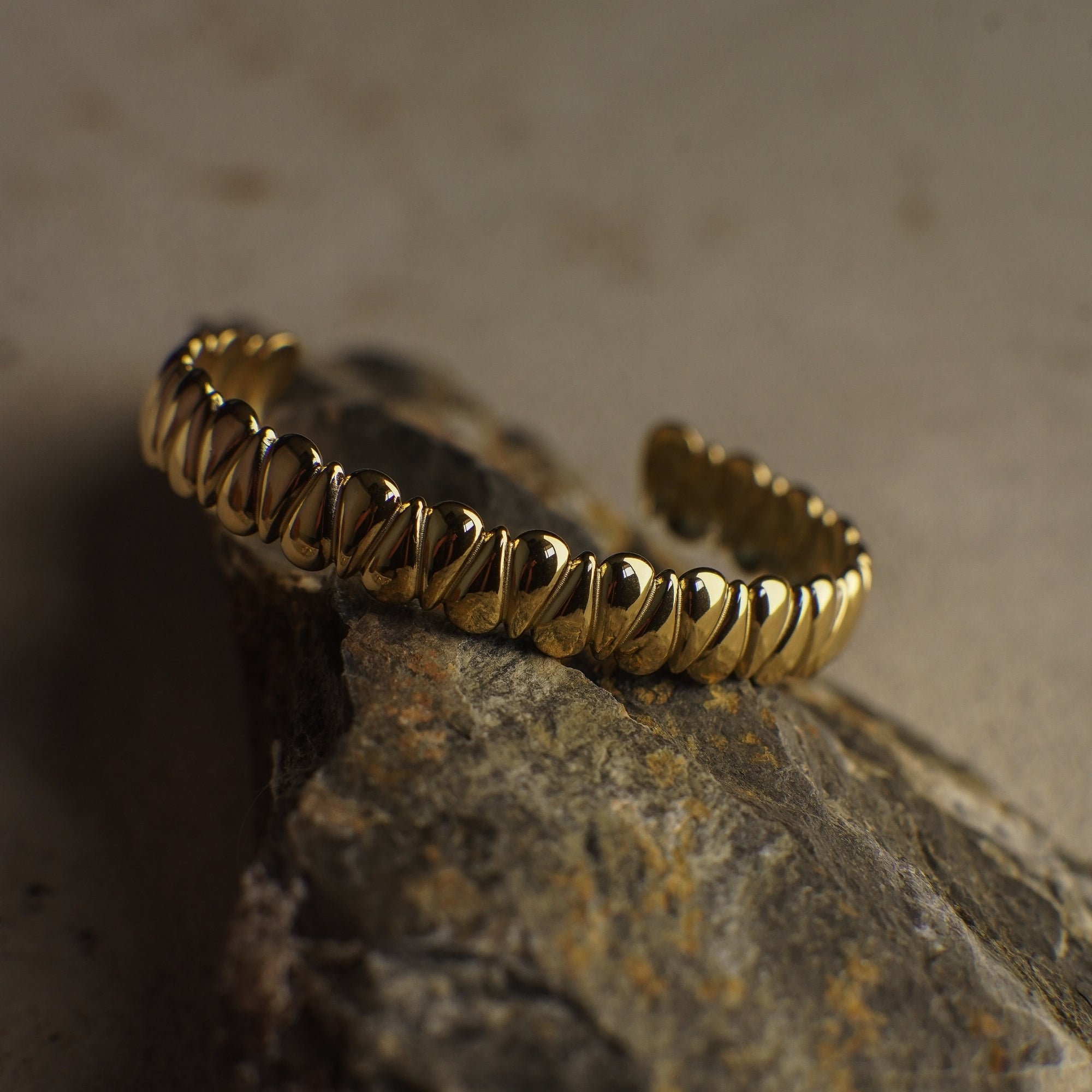 Gold bracelet on a textured stone surface