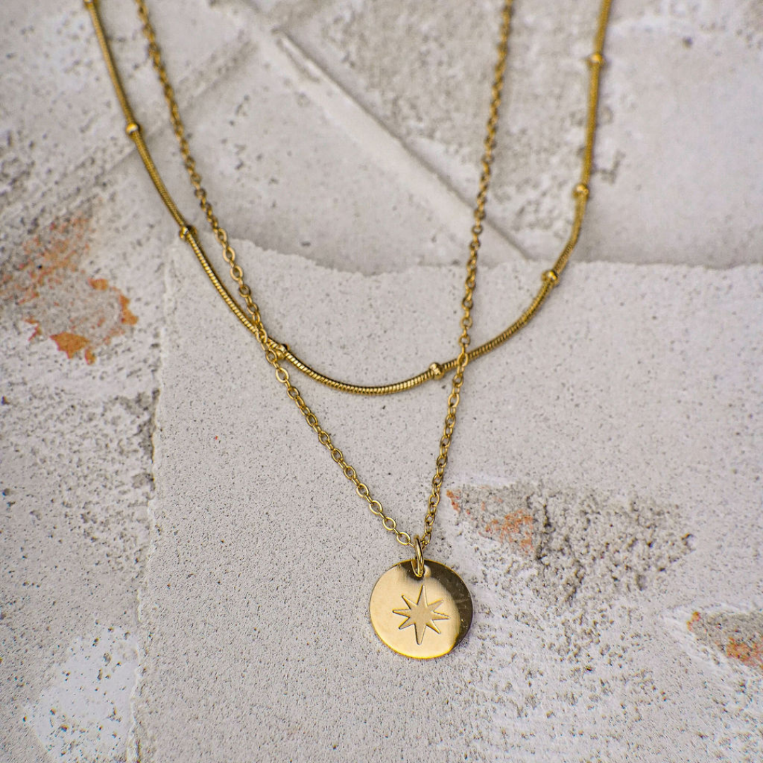 Gold necklace with a star pendant on a textured stone surface