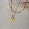 Gold necklace with a star pendant on a textured stone surface
