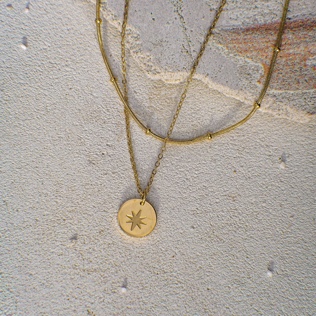Gold necklace with a star pendant on a textured stone surface
