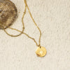 Gold necklace with a star pendant on a textured beige surface