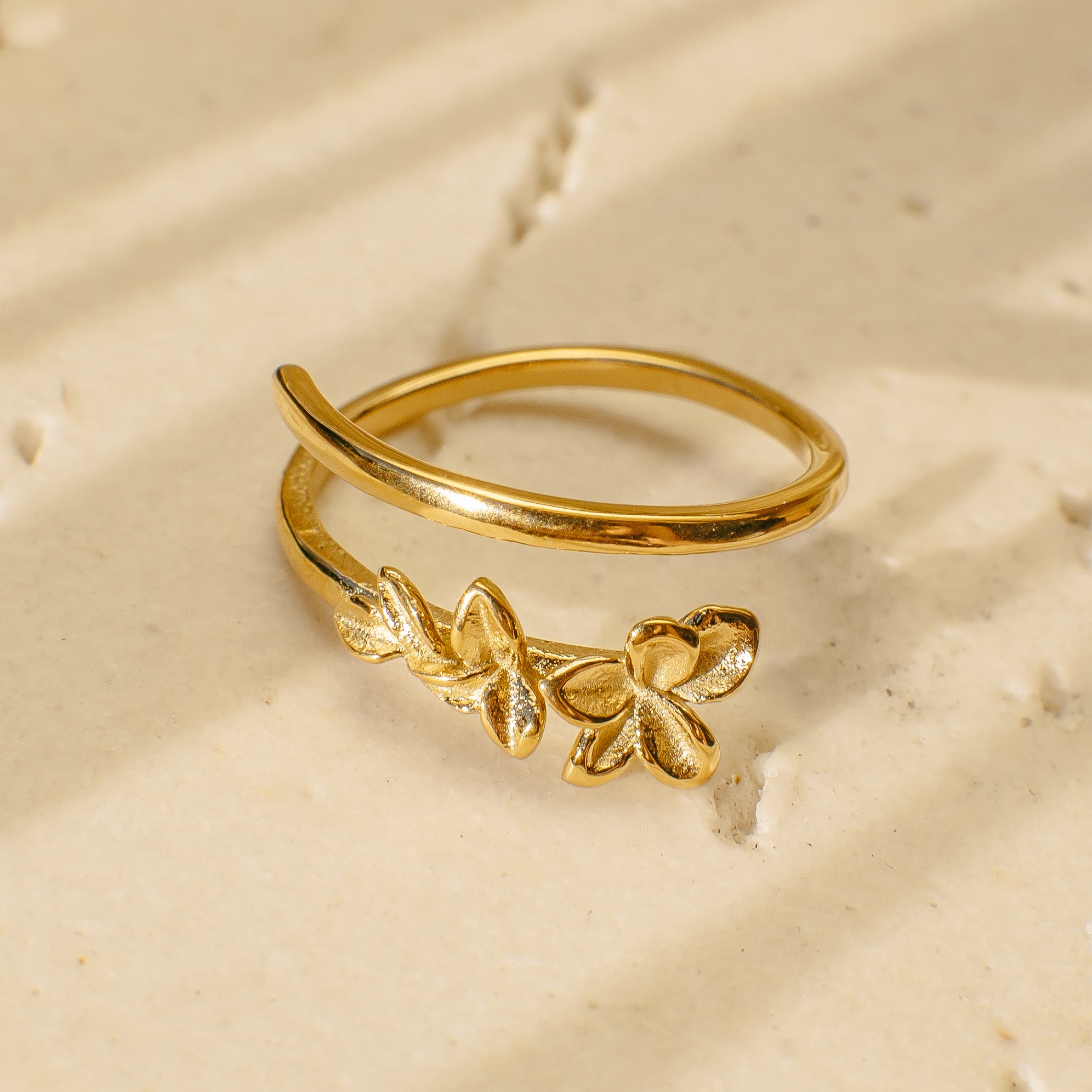 Gold ring with floral design on a beige background