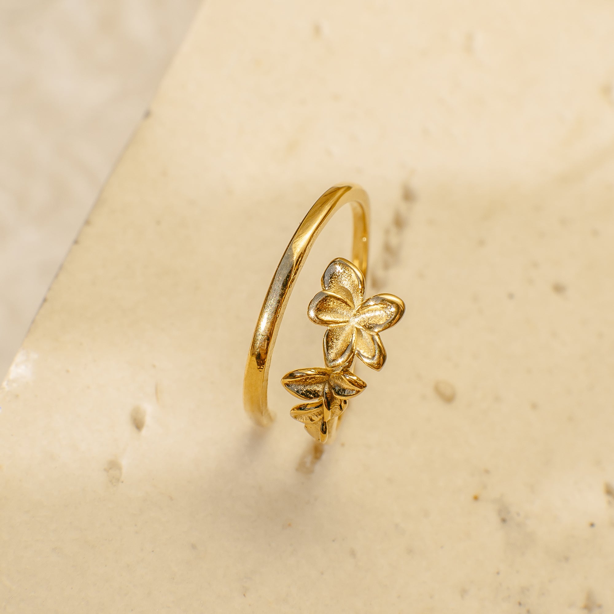 Gold ring with a floral design on a beige surface