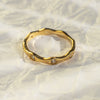Gold ring with diamond accents on a textured white surface