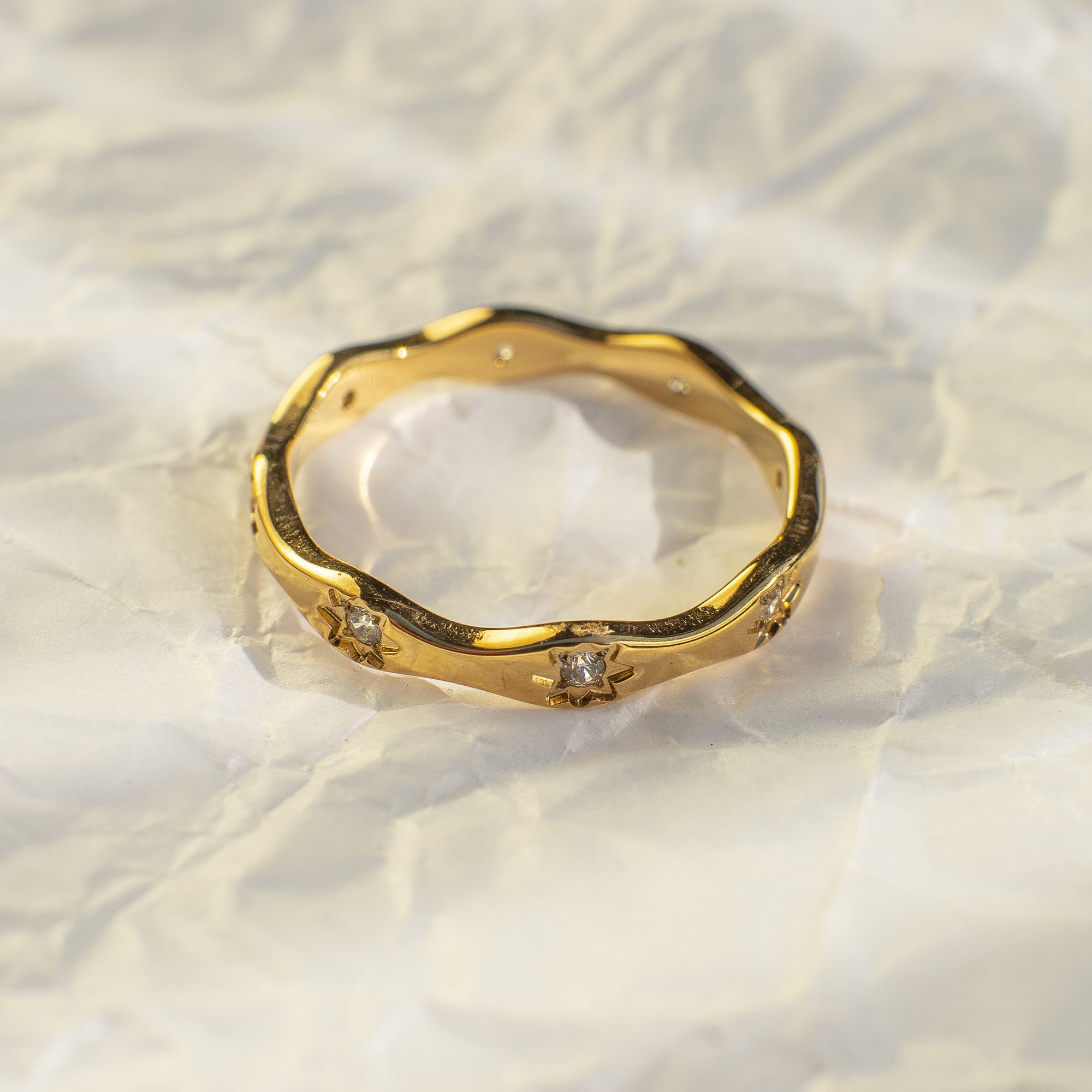 Gold ring with diamond accents on a textured white surface