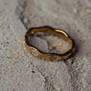 Gold ring with engravings on a sandy surface