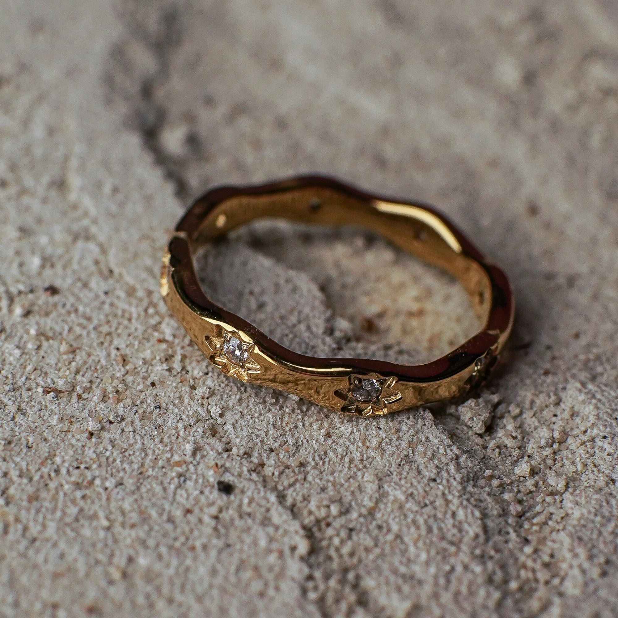 Gold ring with engravings on a sandy surface