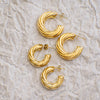 Set of gold hoop earrings on a textured beige surface