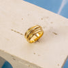 Gold ring on a beige stand with a blue water background