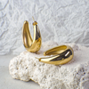 Gold hoop earrings on a textured white surface with a light gray background