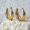 Gold hoop earrings on a textured white surface with a light gray background