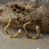 Gold hoop earrings with pearls on a wooden surface