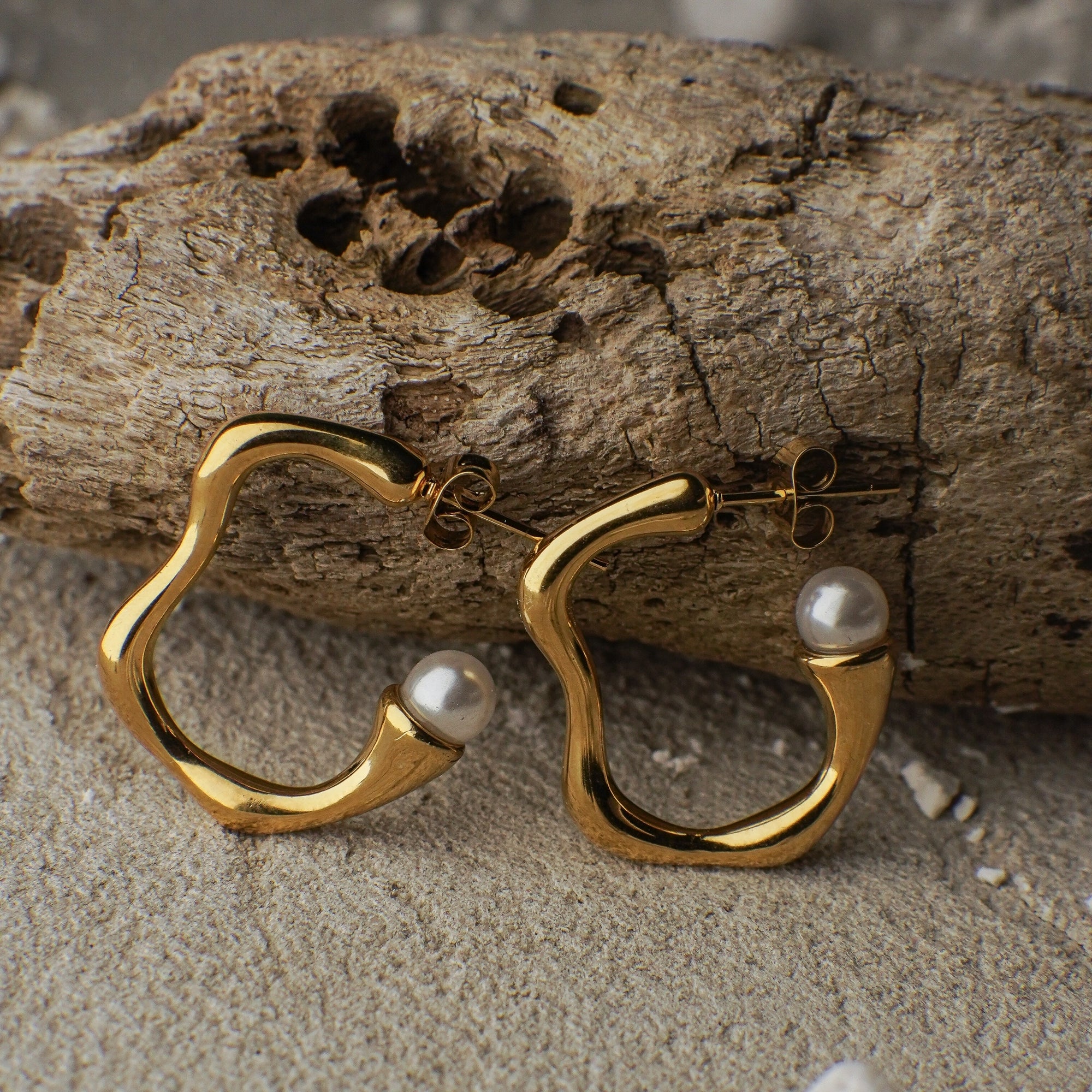 Gold hoop earrings with pearls on a wooden surface