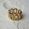 Gold chain-link ring on a sandy surface