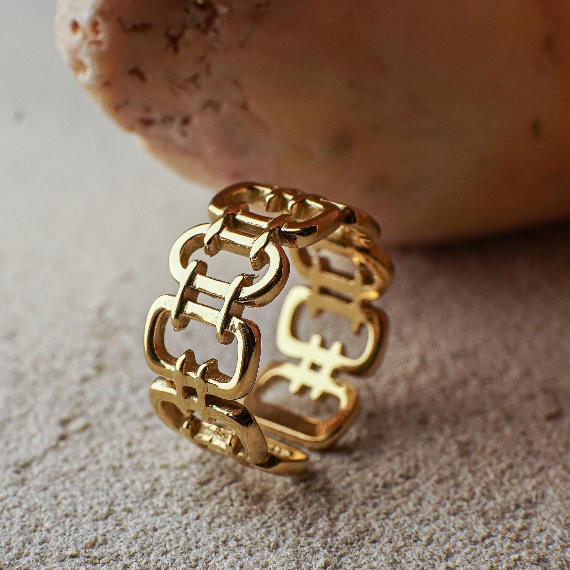Gold chain-style ring on a textured surface