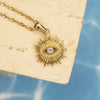 Gold necklace with a star-shaped pendant featuring an eye design on a beige card.