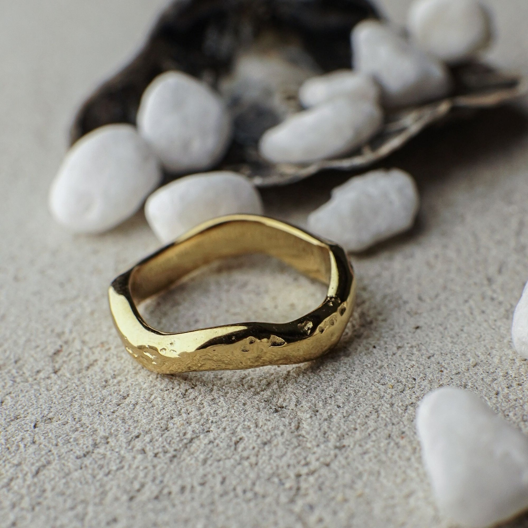 Gold ring on a textured surface with pebbles in the background