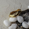 Gold ring on a textured surface with pebbles