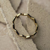 Gold hexagonal ring on a textured beige surface