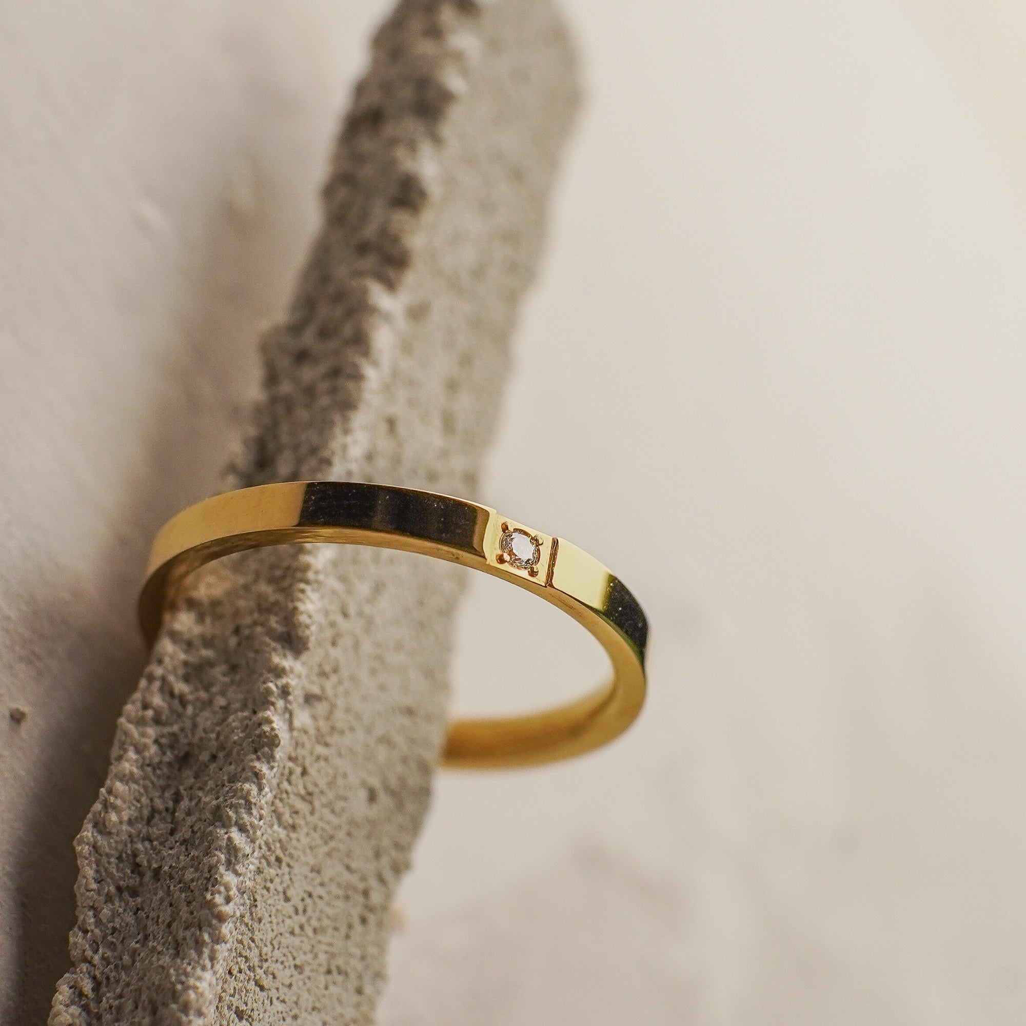 Gold ring with a diamond on a textured stone surface