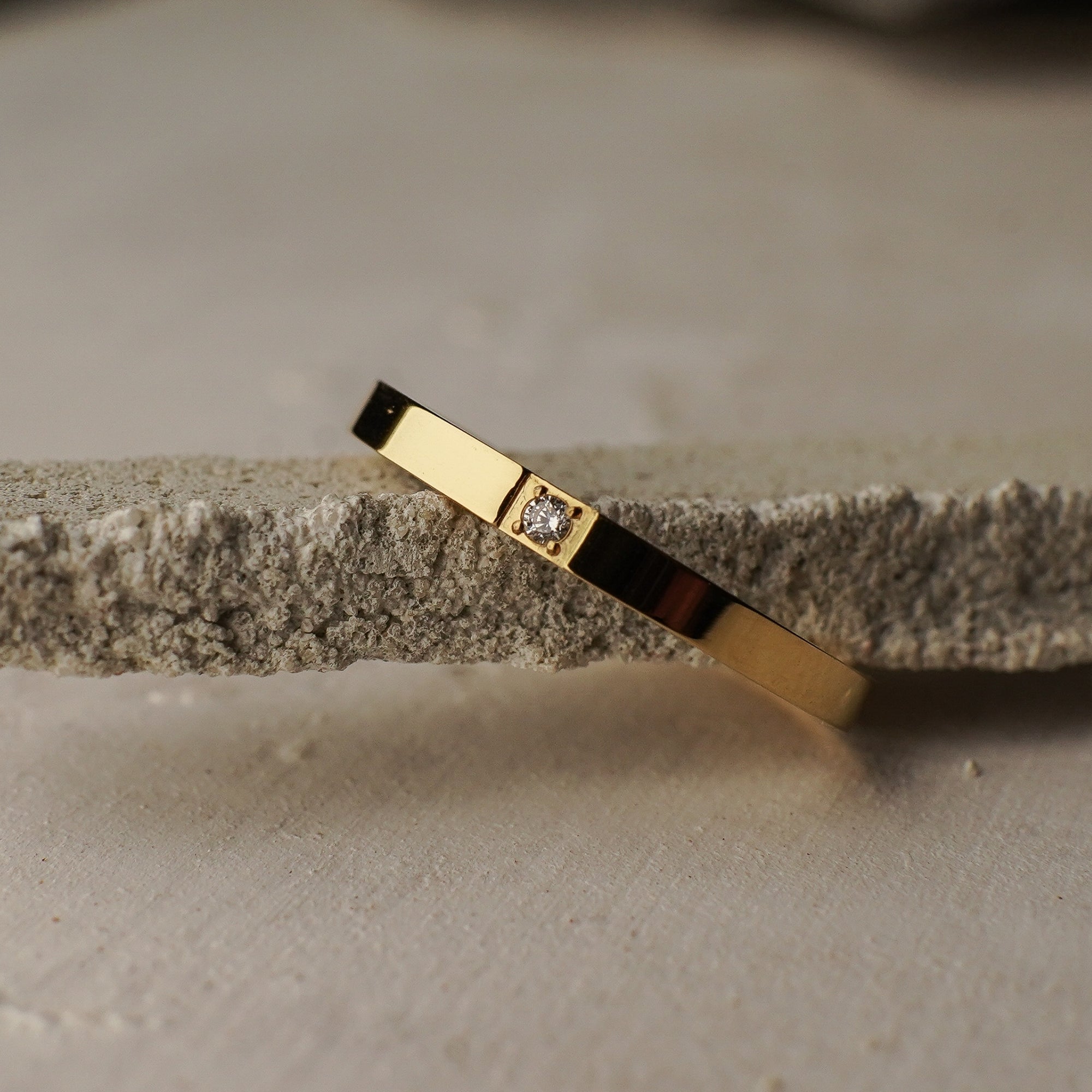 Gold bracelet with a diamond on a textured surface
