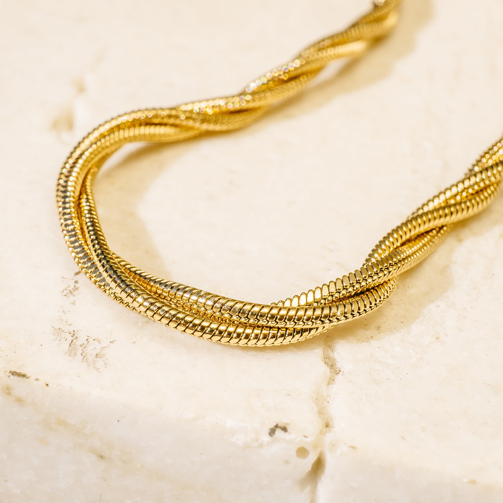 Gold bracelet on a textured beige surface