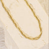 Gold necklace on a textured beige surface