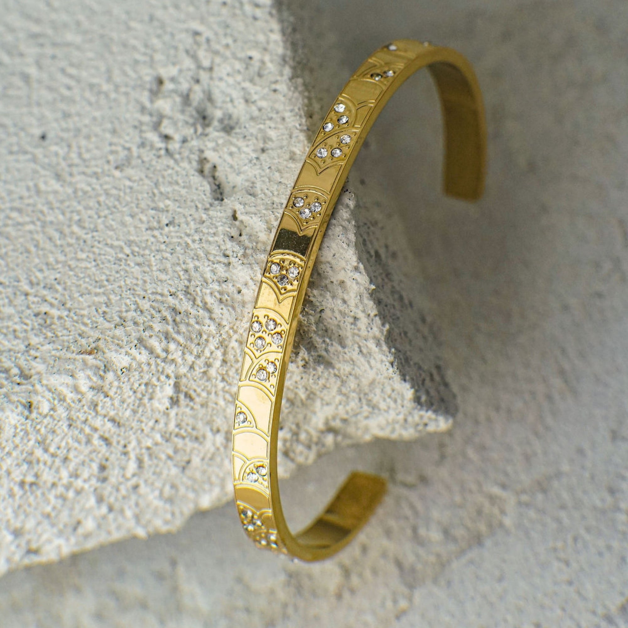 Gold bracelet with diamond accents on a textured stone surface