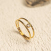 Gold ring with a small diamond on a beige textured surface