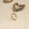 Gold ring with a small diamond on a textured beige surface