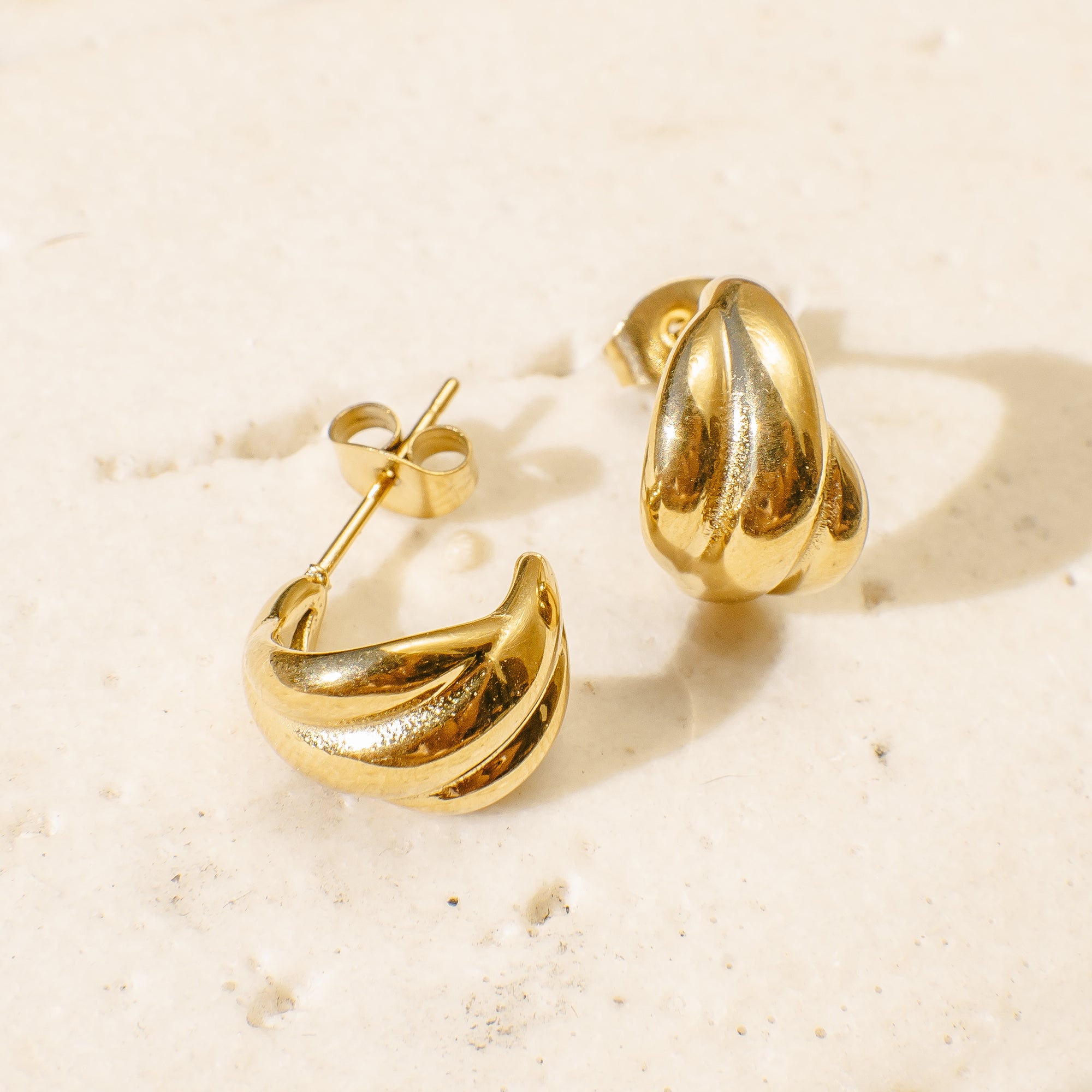 Gold hoop earrings on a light beige surface