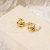 Gold earrings on a beige stone surface