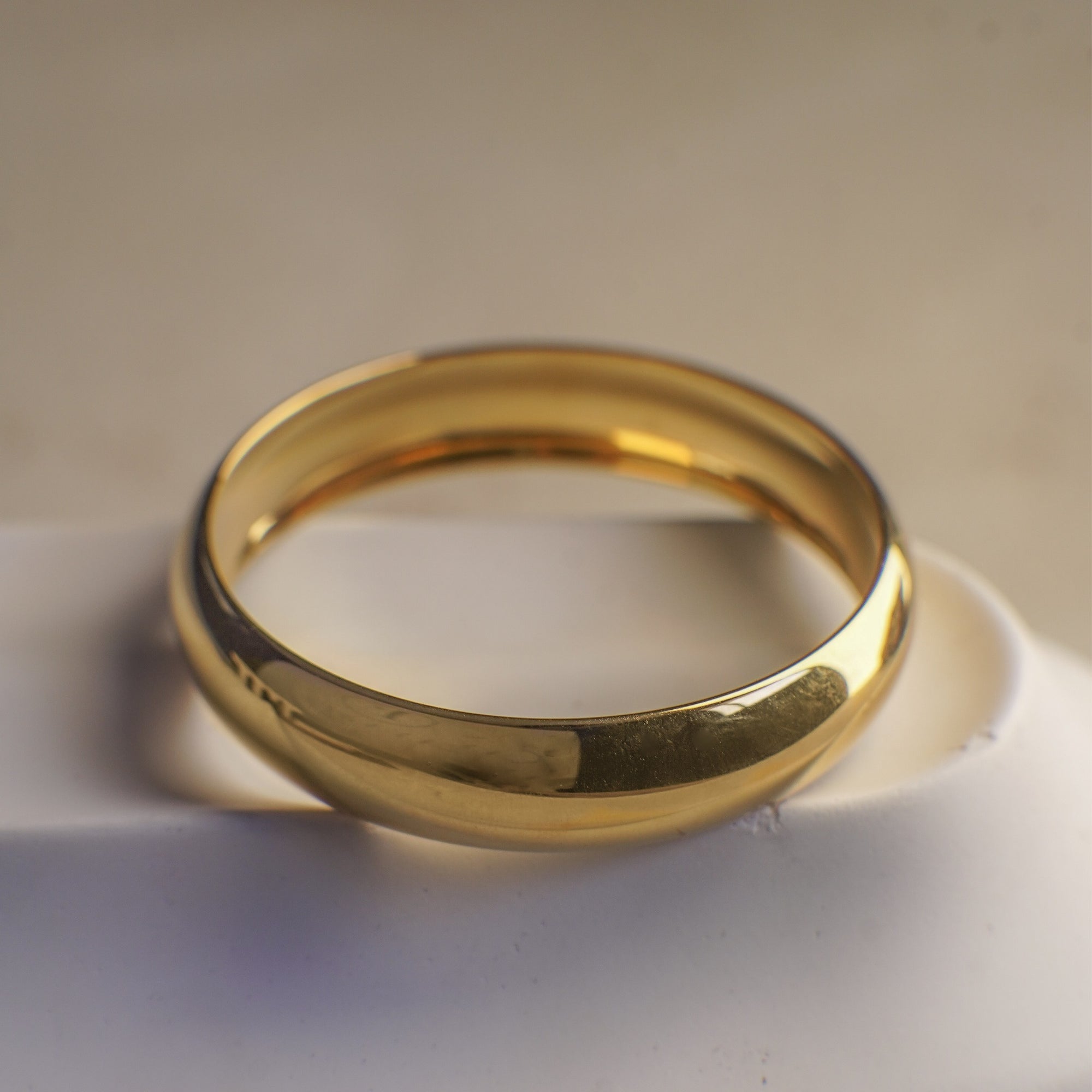 Gold ring on a white surface with a beige background
