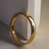 Gold ring on a textured surface with a neutral background