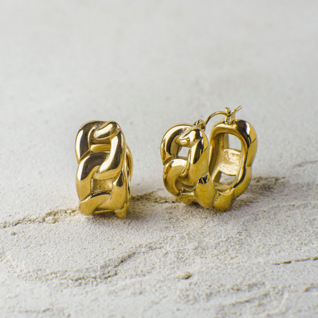Gold hoop earrings on a textured beige surface
